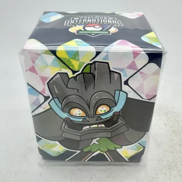 Vista frontal de la Pokémon NA International Championships Competitor Deckbox NAIC 2025, con una ilustración de Ogerpon y el logo del evento en la parte superior, mostrando su diseño exclusivo.